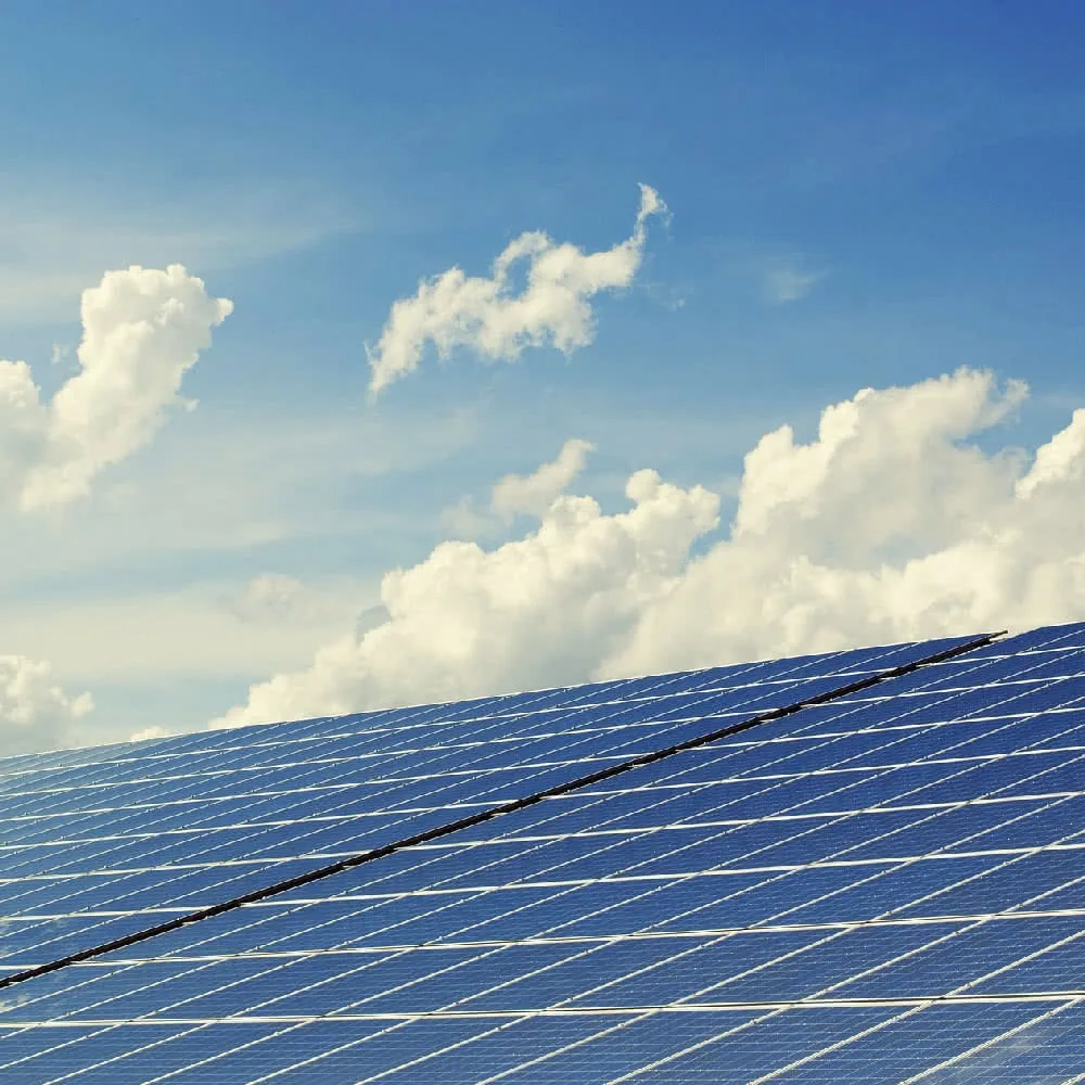 Solar panel array with blue sky and white clouds in background