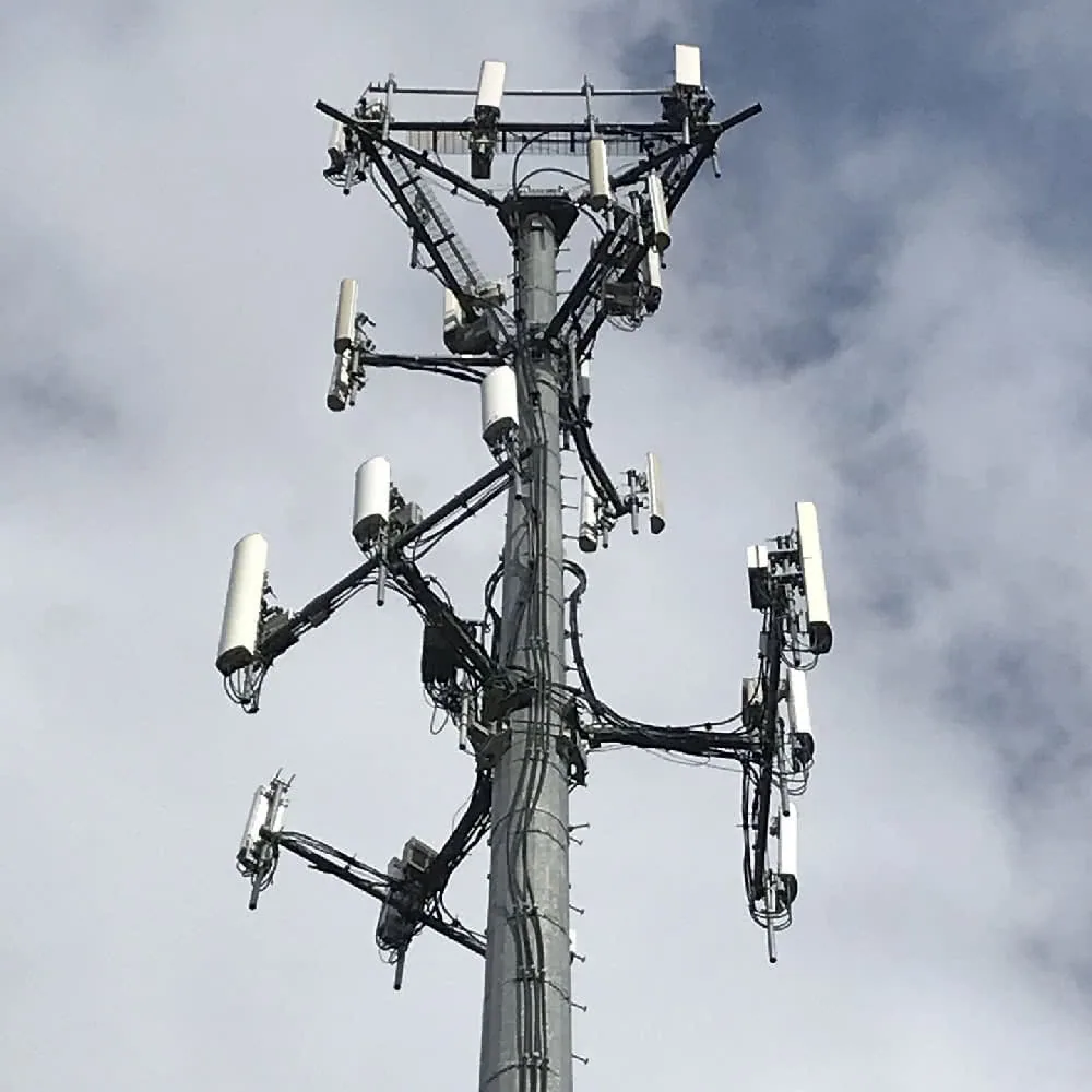 Cellular tower with multiple antennas and transmission equipment mounted on a pole against a cloudy sky
